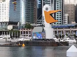 A barge decorated to look like a pelican carrying a jumbotron display, Sydney