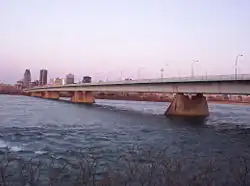 A steel box-girder bridge, with part of the city skyline in the background.
