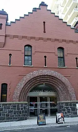 Two story brick building opening onto the sidewalk. Entrance is set in rounded arches.