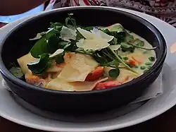 Potato and watercress soup with shaved cheese, tomato and peas