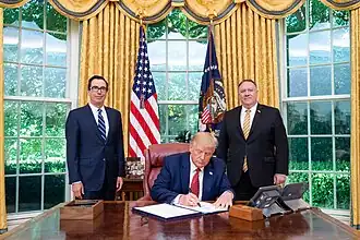 Donald Trump signing the order with Steven Mnuchin and Mike Pence