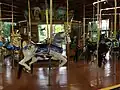 A historic carousel with carousel horses in the foreground and mirrors in the background