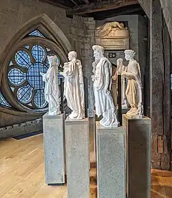 Four white statues of people on pedestals