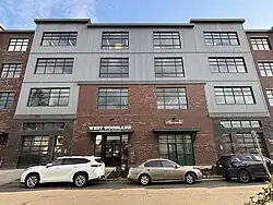 A picture of the Rad Power Bikes headquarters, a four story tall red brick and corrugated metal building that has signs saying "West Woodland Business Center" and "Rad Power Bikes" on it.