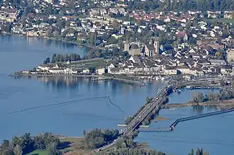 Rapperswil as seen from Etzel mountain: Capuchin monastery to the left, Rapperswil castle and St. John's church in the background, Lake Zurich harbour and Altstadt in the foreground respectively Seedamm, wooden bridge and upper Lake Zurich to the right (October 2010)
