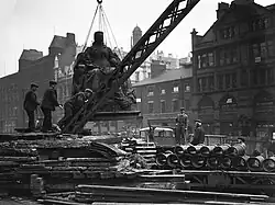 A crane lifts a large statue into the air.