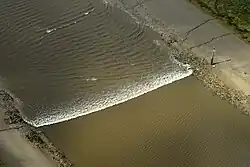 A tidal bore wave moves along the River Ribble between the entrance to the river Douglas and Preston.