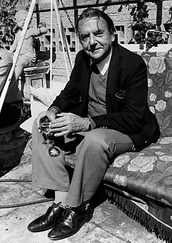 A middle-aged man sits holding a drink.