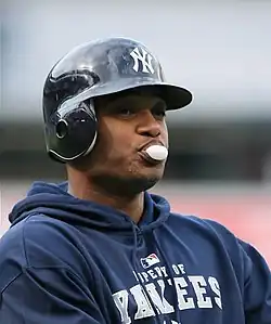 Robinson Canó, in a Yankees batting helmet and sweatshirt, blows a bubble gum bubble.