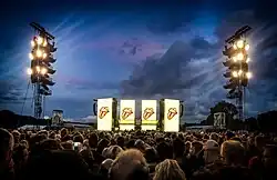 The Rolling Stones Stage at Hamburg Stadtpark. It shows the crowd in the foreground and the huge yellow illuminated screens of the stage in the background.