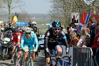 Cyclist Sir Bradley Wiggings leads a small group of riders over a cobbled road section during the race.