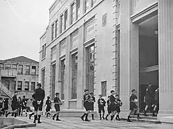 Photo of school boys carrying books into library