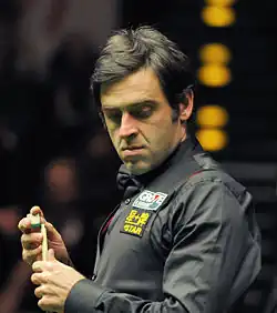 Ronnie O'Sullivan chalking his cue stick.
