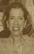 A sepia-colored newspaper photograph of a smiling white woman.