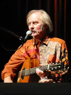 Middle-aged man with beard playing acoustic guitar on stage