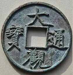 A circular copper coin with a square hole in the center and four Chinese characters, one to each side of the hole, embossed into the body of the coin.