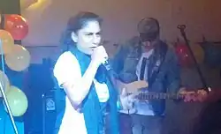 Samira Saraya rapping onstage with System Ali band member playing bass guitar in the background