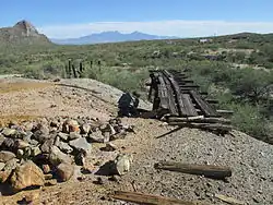 Mine dump and ruins of rail haulage at San Xavier. Helmet Peak is at the left and the Santa Rita Mountains are in the background.