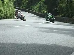 View from Sarah's Cottage towards the Glen Helen area, with Ian Hutchinson cornering inside Ian Lougher in Senior TT during 2010, demonstrating that some places on the course have more variation in racing lines than others[original research?]