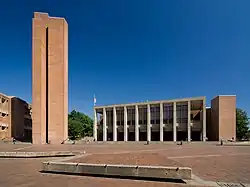 A three-story Brutalist brick building on a large brick plaza