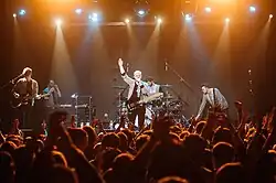 Everything Everything stand on an orange-lit stage in Kiev, Ukraine, mid-performance.