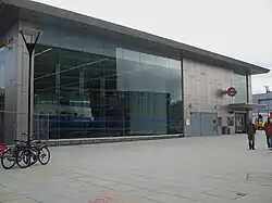 metal and glass building with open front and escalators on Shepherd's Bush Green
