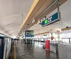 A shot of Simei station's platform, which is underneath its white domed roof. It features a brown electrical box above the station sign, which is the signature colour of the station