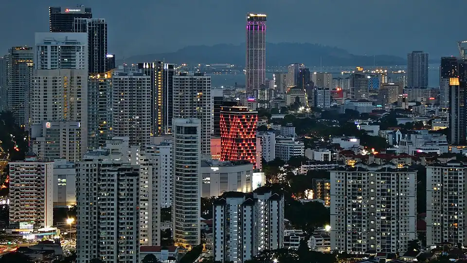A panoramic view of the cityscape, dominated by skyscrapers and apartment blocks, at dusk.