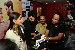 Khan and Sonam Kapoor in front of a bank of microphones and cameras