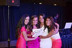Four young women pose holding both each other and an award for "Alpha Gamma Delta: Best Tree"