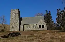 A small stone church on a grassy hillside