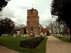 A church tower with prominent buttresses and a small pyramidal roof