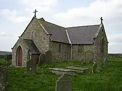 A small stone church seen from the southwest with a south transept as large as the nave