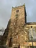 A stone church seen from the south-east with a square, battlemented tower to the left. Part of the body of the church can be seen extending to the right.