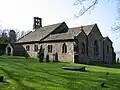 A broad stone church with three gables and a complex bellcote