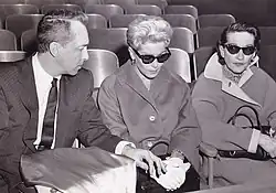 Two women wearing sunglasses seated next to a man