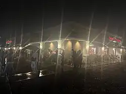 A Sweet Tomatoes Location in the Night with a long line wrapped around the building