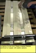 Innards of bus duct showing plastic wrappings of sandwiched busbars and hollow plastic tube spacers.