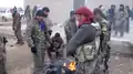 Fighters of the Tell Abyad Revolutionaries Brigade and the YPG warm themselves at a campfire.