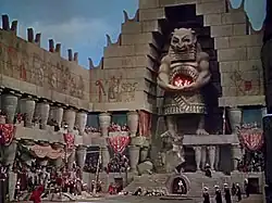 Large pagan temple film set with a large idol in the middle, and surrounded by hieroglyphics and red drapery