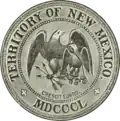 Greyscale drawing of a seal shows 'Territory of New Mexico', 'MDCCCL', and 'crescit eundo' in rings around the edge (separated by crosses patoncé); in the center an American heraldic eagle holding three arrows protects a smaller Mexican heraldic eagle holding a snake and sitting on a nopal.