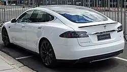 A rear three-quarters view of a white 2015 Tesla Model S