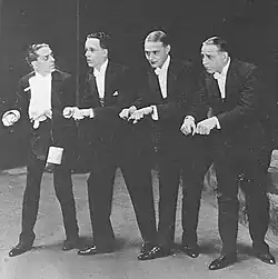 Male vocal quartet in formal evening dress, three of them impeccable in appearance and one (Buchanan) crumpled and frantic