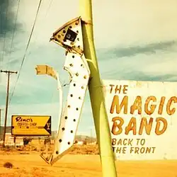 A dilapidated sign with an arrow pointing to the ground in a desert scene and a placard with the name of the album and artist