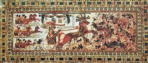 Ancient Egyptian painted wooden panel showing Tutankhamun in a chariot attacking enemies