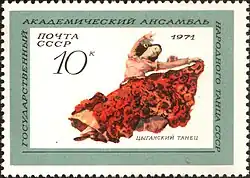 A drawing of a female dancer in a traditional Romani dress in the middle of a jump, with arms outstretched. The skirt is red and the top is pink.