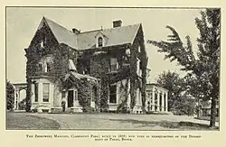 Photograph of a two-and-a-half story house. Much of the structure is covered with ivy, giving the impression of age.