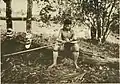 A Dayak man from Sabah, Malaysia tying a spearhead on a sumpitan (c. 1912)
