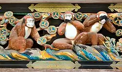 A wooden polychrome carving of three wise monkeys on one of the walls of the temple complex