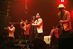 A picture of a group of men on a stage in white jackets performing jazz instruments.